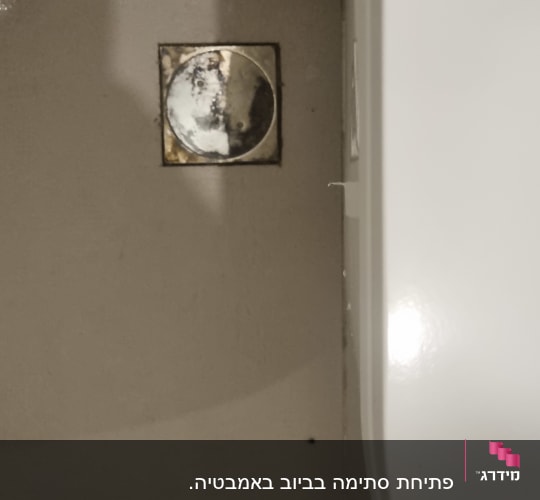 פתח ניקוז עגול ברצפה ליד קיר לבן